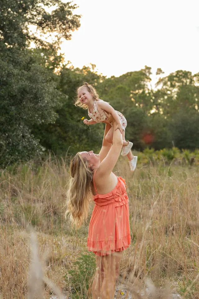 Mom lifting her daughter into the air at golden hour