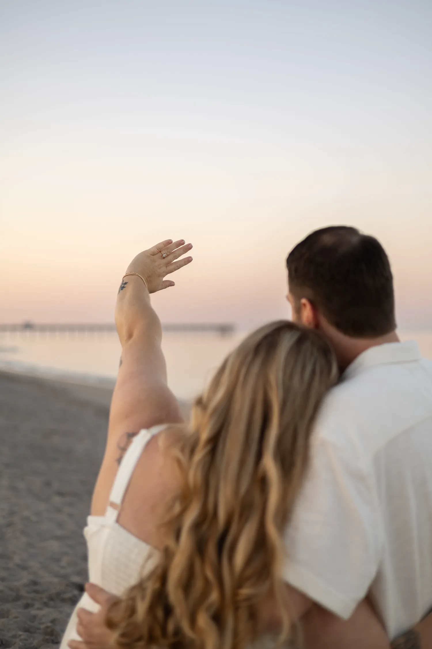 Expecting couple watching the sunset by the pier