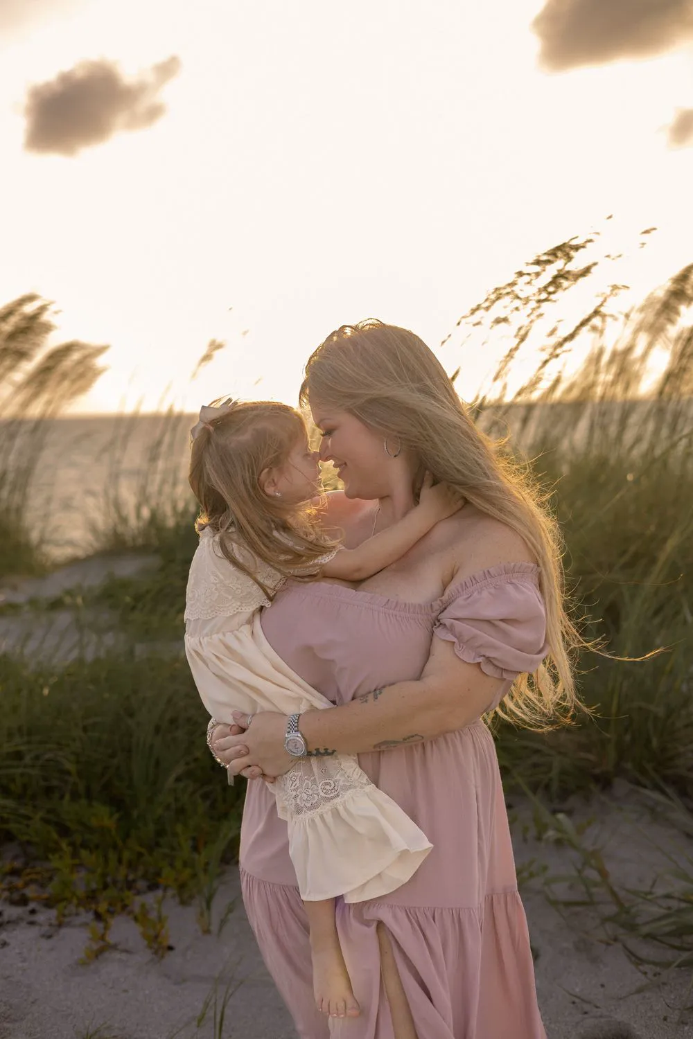 Mom and daughter cuddling in the sea oats