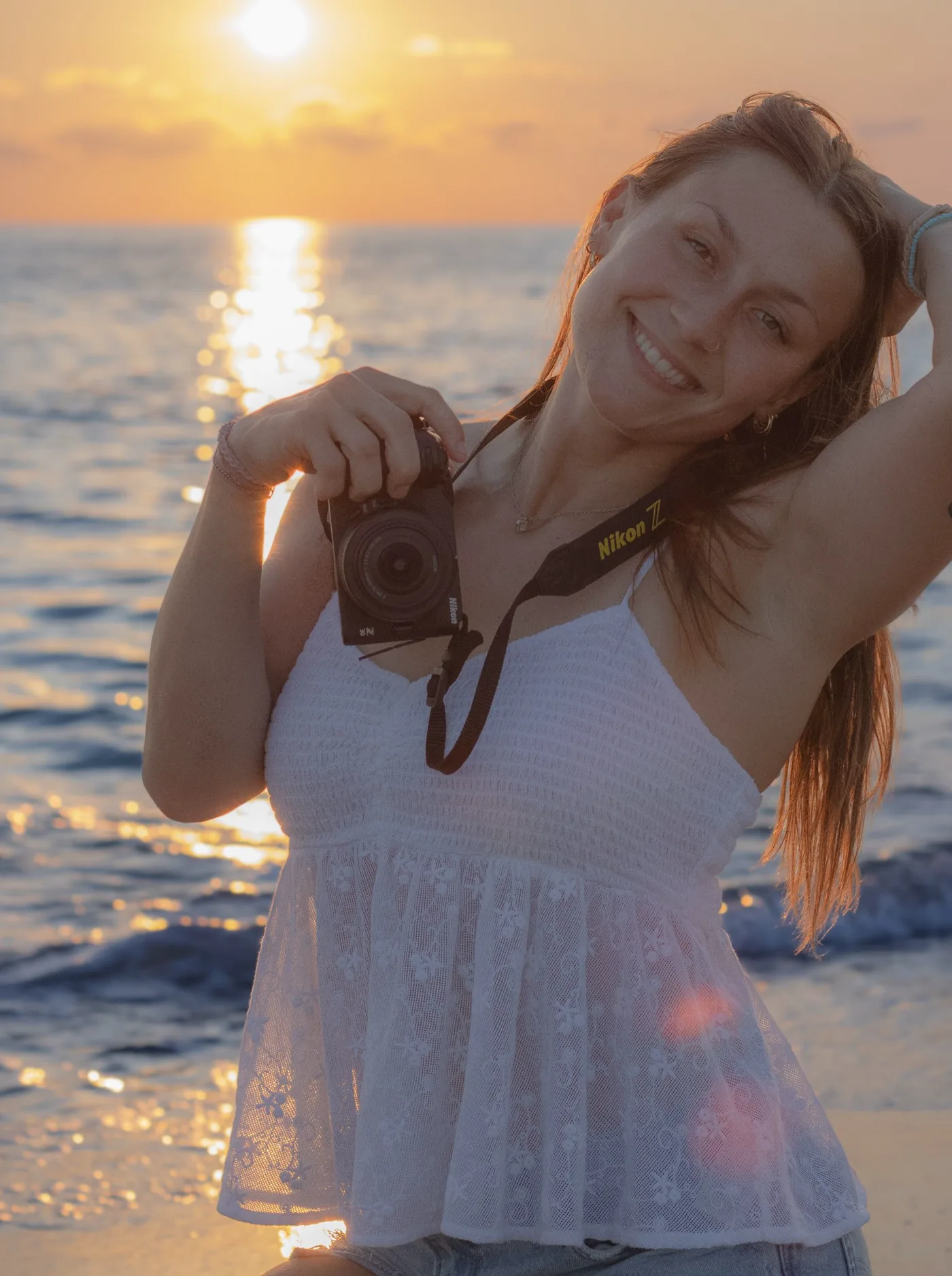 Elyssa smiling with her camera at sunset on the beach